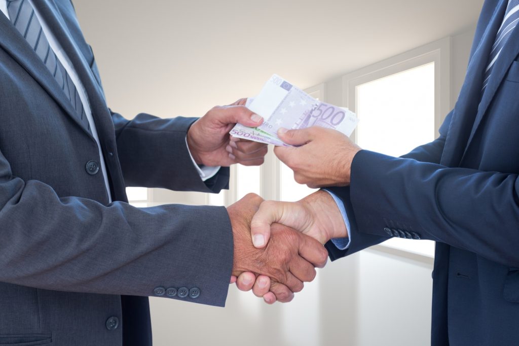 Persona siendo sobornada por otra por medio de dinero.